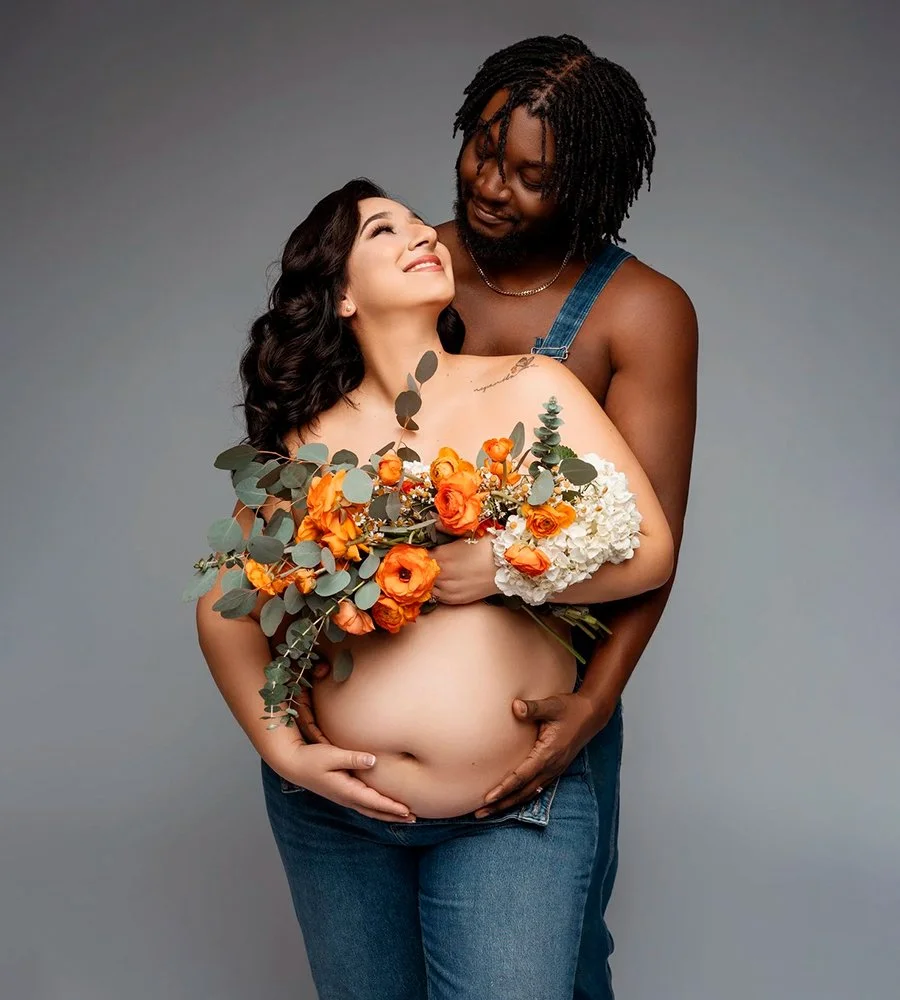 A pregnant woman in a dress gently cradling her belly during a maternity photoshoot.